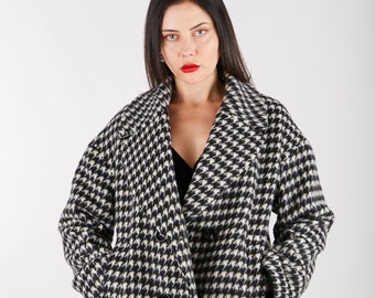 May include: A black and white houndstooth patterned coat with a double breasted closure. The coat has a collar and pockets.