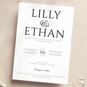 May include: A white wedding invitation with black text. The invitation reads "Lilly & Ethan" and includes the date and time of the wedding, the location, and the RSVP information.