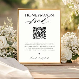 Könnte beinhalten: Ein weißes Schild mit schwarzem Text und einem schwarz-weißen QR-Code. Der Text lautet "Flitterwochen-Fonds" und "Wir haben das Glück, ein Zuhause voller Dinge zu haben, die wir brauchen. Wenn Sie uns ein Hochzeitsgeschenk machen möchten, wären wir Ihnen sehr dankbar, wenn Sie Beiträge für unsere Flitterwochen leisten würden, indem Sie den QR-Code oben scannen." Das Schild ist mit "Amanda & Michael" unterschrieben.