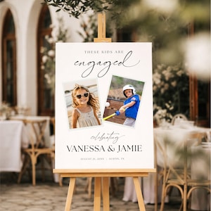 Könnte beinhalten: Ein weißes, rechteckiges Hochzeitsschild auf einer Holzstaffelei mit dem Text "THESE KIDS ARE engaged" und "celebrating VANESSA & JAMIE AUGUST 21, 20XX | AUSTIN, TX". Es enthält zwei quadratische Fotos von Kindern, eines mit Sonnenbrille und eines beim Baseball.