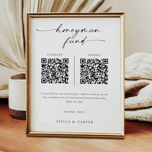 Könnte beinhalten: Ein weißes Schild mit goldenem Rahmen, auf dem der Text "honeymoon fund" in schwarzer Kursivschrift steht. Das Schild zeigt zwei QR-Codes, einer mit der Bezeichnung "CashApp" und der andere mit der Bezeichnung "Venmo". Der Text unter den QR-Codes lautet: "Wenn Sie Spaß hatten und uns ein Geschenk für unsere Reise machen möchten, wäre eine Spende an unseren Hochzeitsfonds wirklich toll! Vielen Dank! Stella & Carter"