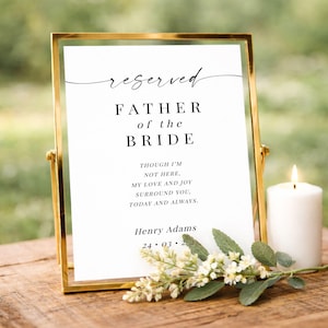 Könnte beinhalten: Ein goldgerahmtes Schild mit dem Text "reserved FATHER of the BRIDE". Eine weiße Kerze und ein Blumenarrangement befinden sich neben dem Schild. Der Text enthält den Namen "Henry Adams" und ein Datum.