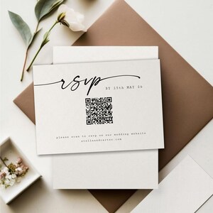 以下が含まれることがあります： 白いRSVPカードに黒い文字で「RSVP 5月15日までに」と書いてあります。テキストの下には白黒のQRコードがあり、QRコードの下には「結婚式ウェブサイトstellalandcarter.comでRSVPするには、スキャンしてください」という文字があります。