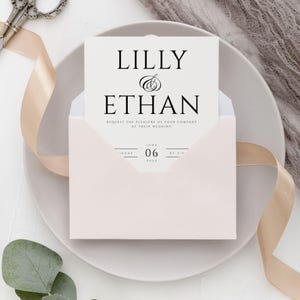 May include: A white wedding invitation with black text announcing the wedding of Lilly and Ethan on June 06, 2022.