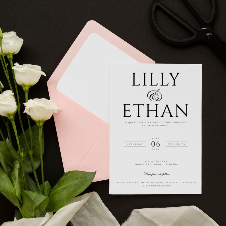 May include: A white wedding invitation with black text. The invitation reads "Lilly & Ethan" and includes the date and time of the wedding, the location, and the RSVP information.