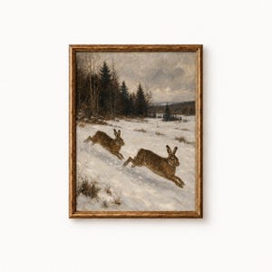 May include: A framed oil painting depicting two brown hares running across a snow-covered field. In the background, a dark forest of pine trees stands under a cloudy, overcast sky. The artwork is enclosed in a textured, metallic gold frame.
