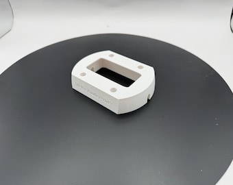 Puede incluir: Un componente rectangular blanco impreso en 3D con esquinas redondeadas y un recorte rectangular central. El objeto presenta cuatro pequeños orificios circulares en su superficie superior y el texto 3D By Anderzonic en relieve en el lateral.