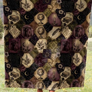Peut inclure: Une grande couverture à motifs avec un motif répété de symboles mystiques dans les tons de marron, noir et or. La couverture est présentée sur fond de champ vert et de chaîne de montagnes.