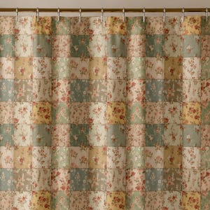 May include: A shower curtain featuring a patchwork design of alternating squares in muted sage green, soft yellow, and cream, each decorated with a delicate floral pattern. The curtain hangs from a metal rod with rings and covers a white bathtub.