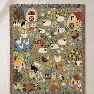 Peut inclure: Un plaid tissé sur fond vert représentant une scène de ferme. Le motif comprend des granges, des maisons, des arbres, des fleurs, des citrouilles et divers animaux comme des moutons, des chats, des poules, des canards et un coq, avec des franges.