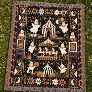 May include: A rectangular woven throw blanket featuring a black background with a repeating pattern of white ghosts wearing party hats, orange pumpkins, black cats, and circus-themed elements like a carousel, tents, and balloons with fringed edges.