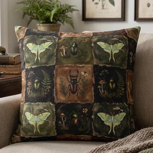 May include: Square throw pillow with a patchwork design featuring insects and botanical illustrations in shades of green, brown, and black. The pillow is on a beige sofa with a green and brown knitted throw.