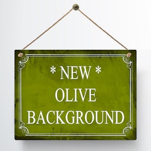 May include: A rectangular sign with an olive green background and white text that reads "* NEW * OLIVE BACKGROUND". The sign is framed with a white border and decorative corner elements. It hangs from a brown rope.