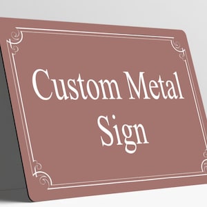 May include: A rectangular metal sign with a dusty rose background and rounded corners. The sign features a white border with decorative scrollwork at each corner and the white text Custom Metal Sign centered on the front surface.