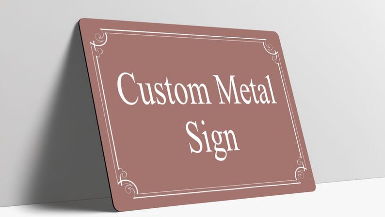 May include: A rectangular metal sign with a dusty rose background and rounded corners. The sign features a white border with decorative scrollwork at each corner and the white text Custom Metal Sign centered on the front surface.