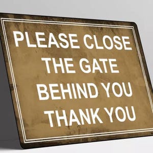 Op de afbeelding: Een rechthoekig bord met een bruine achtergrond en witte tekst: "PLEASE CLOSE THE GATE BEHIND YOU THANK YOU." Het bord heeft een witte rand en een verweerde textuur.
