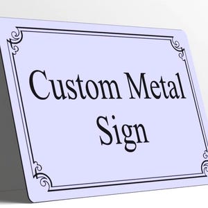 May include: A rectangular light blue metal sign with rounded corners and a black decorative border. The text Custom Metal Sign is printed in the center in a black serif font. The sign is positioned at an angle against a white surface.