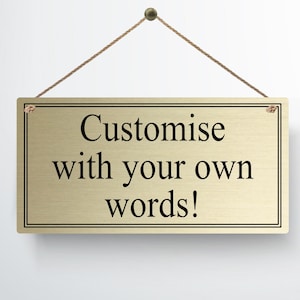 Könnte beinhalten: Ein goldfarbenes Metallschild mit schwarzem Text, der "Customise with your own words!" lautet, hängt an einer Schnur.
