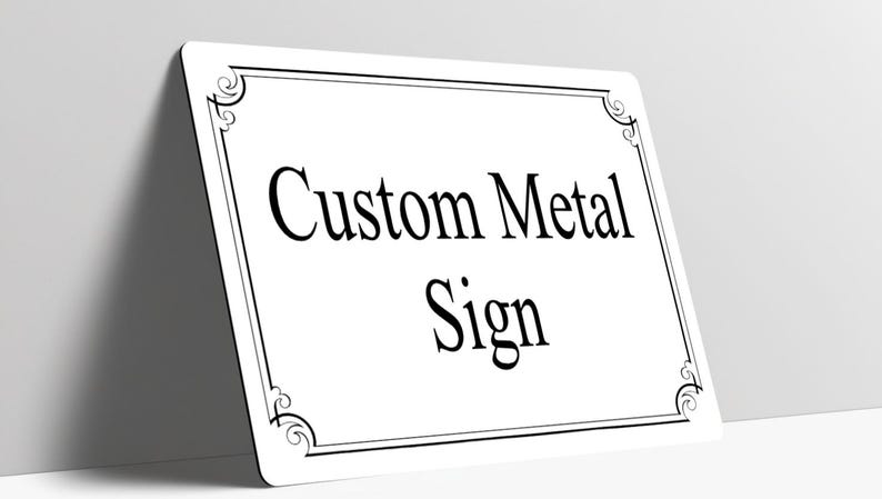 May include: A rectangular white metal sign with rounded corners, featuring a black decorative border with scrollwork at each corner. The text Custom Metal Sign is printed in the center in a black serif font, oriented horizontally.