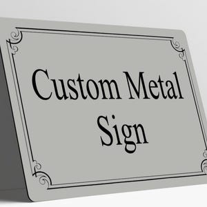 May include: A rectangular light gray metal sign with rounded corners, featuring a black decorative border and the black text Custom Metal Sign centered on the surface. The sign is positioned at an angle against a plain white background.