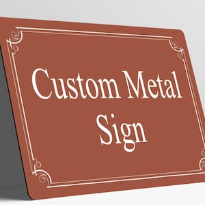 May include: A rectangular metal sign with a terracotta-colored background and rounded corners. The sign features a white border with decorative scrollwork at each corner and the white text Custom Metal Sign centered on the surface.