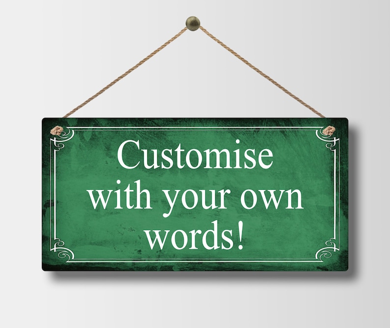 May include: A rectangular, dark green sign with white text that reads "Customise with your own words!" The sign is framed with a white border and decorative corner elements. It hangs from a natural rope.