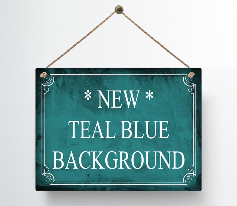 May include: A rectangular teal blue sign with white text that reads "* NEW * TEAL BLUE BACKGROUND". The sign is framed with a white border and decorative corner elements, and is suspended by a brown rope.