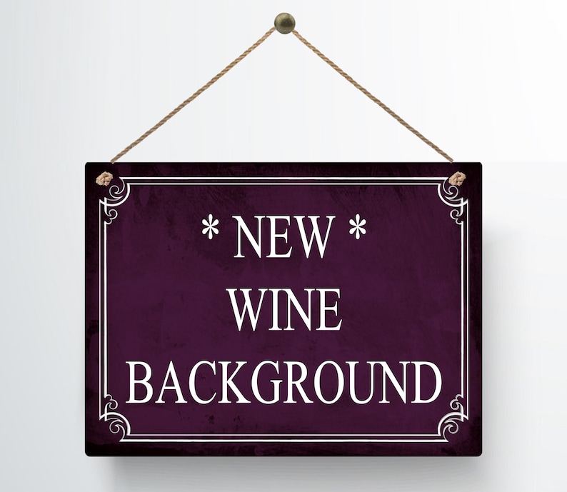 May include: A rectangular sign with a dark purple background and white text that reads "* NEW * WINE BACKGROUND". The sign is framed with a white border and decorative corner elements. It hangs from a brown string.