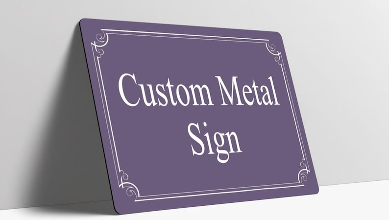 May include: A rectangular purple metal sign with rounded corners featuring a white border with decorative corner flourishes. The text Custom Metal Sign is printed in the center in a white serif font. The sign is positioned at an angle.