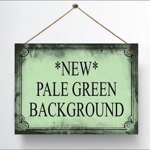 May include: A rectangular sign with a pale green background and black text that reads "*NEW* PALE GREEN BACKGROUND". The sign is framed with a black border and decorative corner elements, and is suspended by a brown rope.
