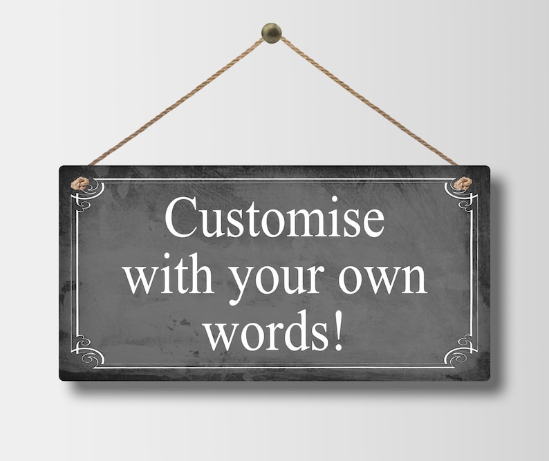 May include: A rectangular, dark gray sign with white text that reads "Customise with your own words!". The sign is framed with a white border and decorative corner elements. It hangs from a brown rope.
