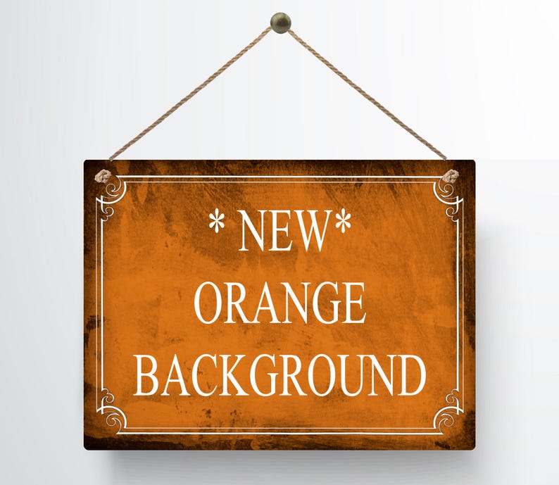 May include: A rectangular wooden sign with an orange background and the words "NEW ORANGE BACKGROUND" in white. The sign is framed with a decorative white border and is suspended by a brown rope.