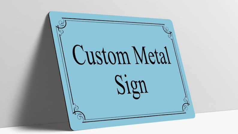 May include: A rectangular light blue metal sign with rounded corners and a black decorative border. The text Custom Metal Sign is printed in the center in a black serif font. The sign is positioned at an angle against a plain surface.