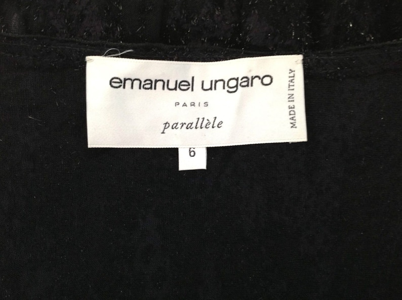 May include: A close-up of a black garment with a white label. The label reads "emanuel ungaro PARIS parall&egrave;le" with the number "6" below. The words "MADE IN ITALY" are also visible on the label.