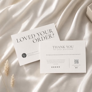 Può includere: Due biglietti bianchi con testo nero su sfondo di raso bianco. Un biglietto recita "LOVED YOUR ORDER?" e l'altro dice "THANK YOU for your purchase". I biglietti includono un logo e informazioni sul sito web.