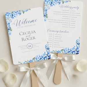 Pode incluir: Dois leques retangulares de programa de casamento com cantos arredondados, decorados com ilustrações de hortênsias azuis. O texto diz Welcome to the wedding of Cecilia and Roger, August 21, 2026, e Wedding party com um cronograma da cerimônia. Cada um tem um cabo de madeira e uma fita branca.