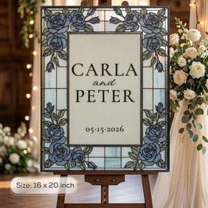 May include: A rectangular stained glass sign measuring 16 by 20 inches, featuring a border of blue roses and green leaves. The center panel displays the text CARLA and PETER with the date 05.15.2026 in a black serif font on a light background.