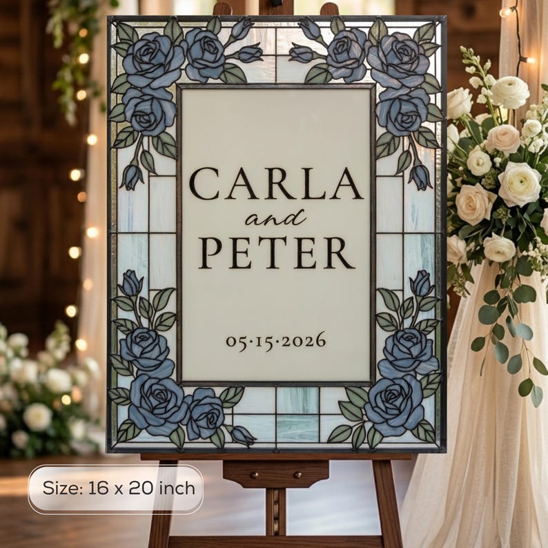 May include: A rectangular stained glass sign measuring 16 by 20 inches, featuring a border of blue roses and green leaves. The center panel displays the text CARLA and PETER with the date 05.15.2026 in a black serif font on a light background.