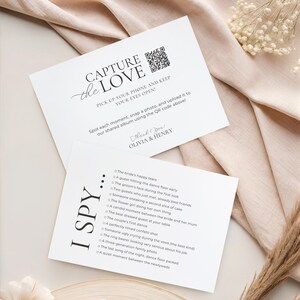 May include: Two white rectangular wedding cards with black text. The top card reads CAPTURE THE LOVE with a QR code and instructions. The bottom card is titled I SPY and lists various wedding moments to photograph, including the bride's happy tears.