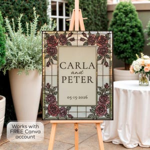 May include: A rectangular sign featuring a stained glass style border with dark pink roses and green leaves. The center panel is cream colored with the text CARLA and PETER and the date 05.15.2026 in a dark serif font. The sign rests on a wooden easel.