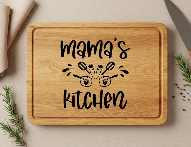 May include: A wooden cutting board with the text "Mama's Kitchen" in black lettering. The text is surrounded by a design of two pots with hearts and carrots.
