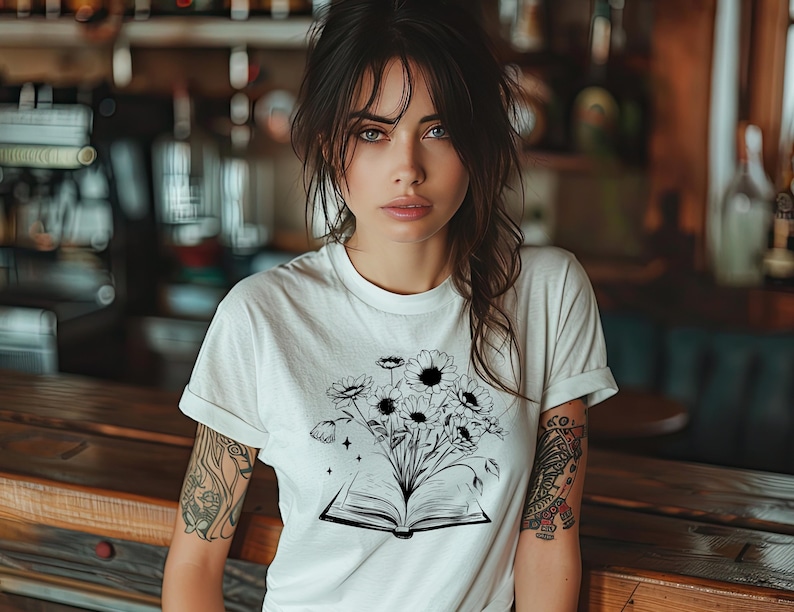 May include: A white t-shirt with a black and white graphic of an open book with flowers growing out of it.