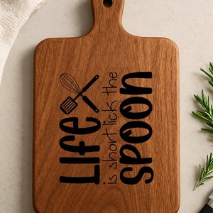May include: A wooden cutting board with a handle, engraved with the text "Life is short, lick the spoon".