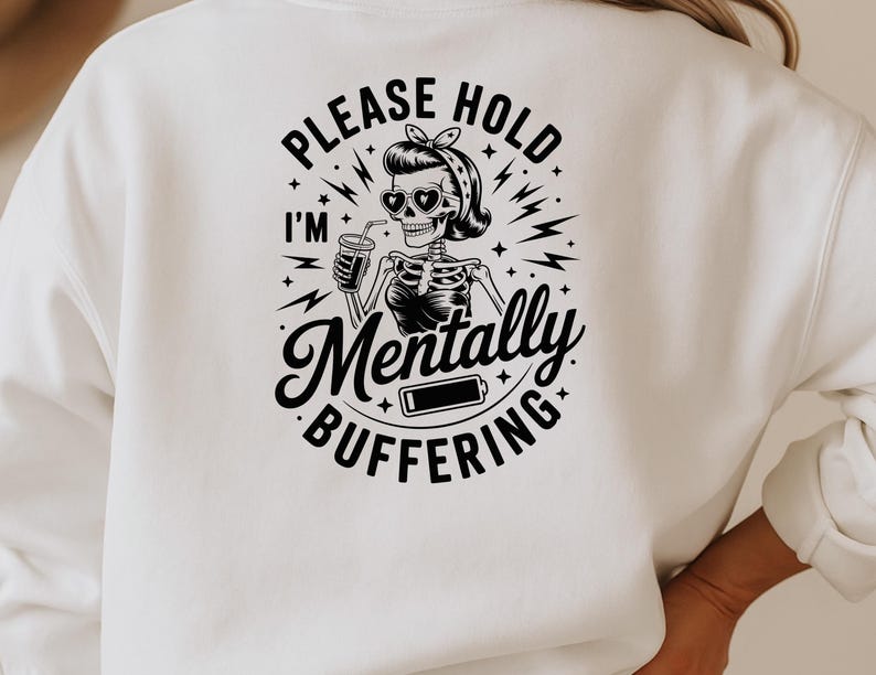 May include: White sweatshirt with a black graphic on the back. The graphic features a skeleton wearing sunglasses and a headscarf, holding a drink. Text reads "PLEASE HOLD I'M Mentally BUFFERING" with a low battery icon.