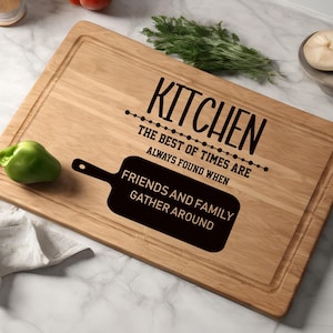 May include: A wooden cutting board with the text "Kitchen: The best of times are always found when friends and family gather around".