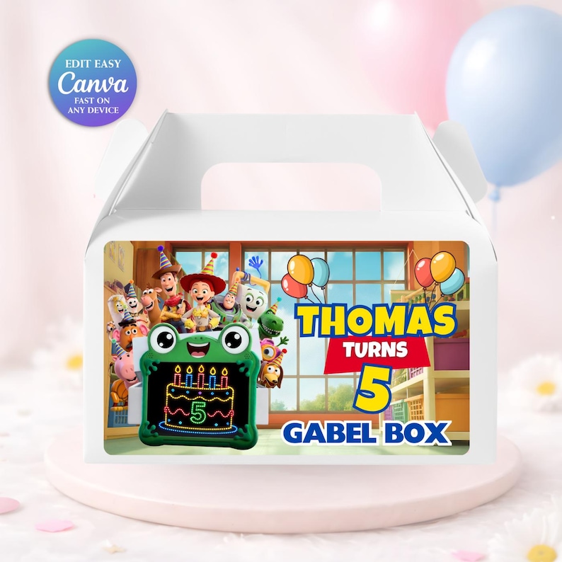 May include: A white gable box featuring a colorful graphic of animated characters, a green frog-shaped drawing tablet with a birthday cake illustration, and the text "THOMAS TURNS 5 GABEL BOX" printed in bold blue and red lettering on the front panel.