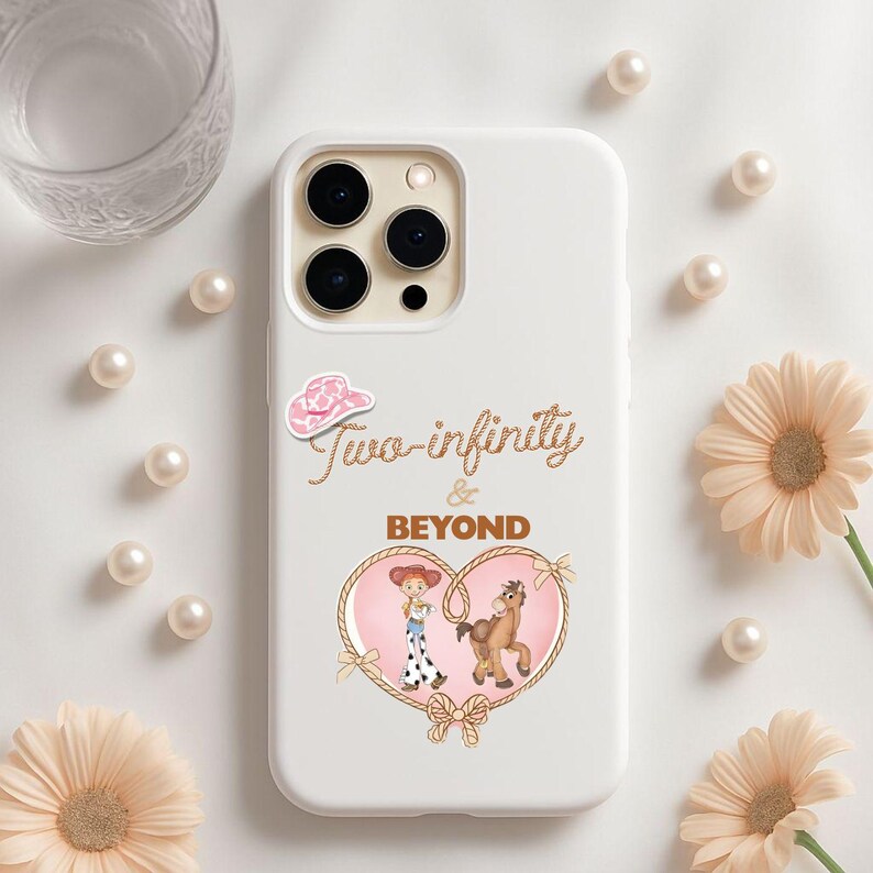 Peut inclure: Coque de t&eacute;l&eacute;phone blanche avec un motif repr&eacute;sentant un chapeau de cow-boy rose, le texte "Two-infinity & BEYOND" et une illustration en forme de c&oelig;ur d'une cowgirl et d'un cheval. La coque est d&eacute;cor&eacute;e de perles et de fleurs.