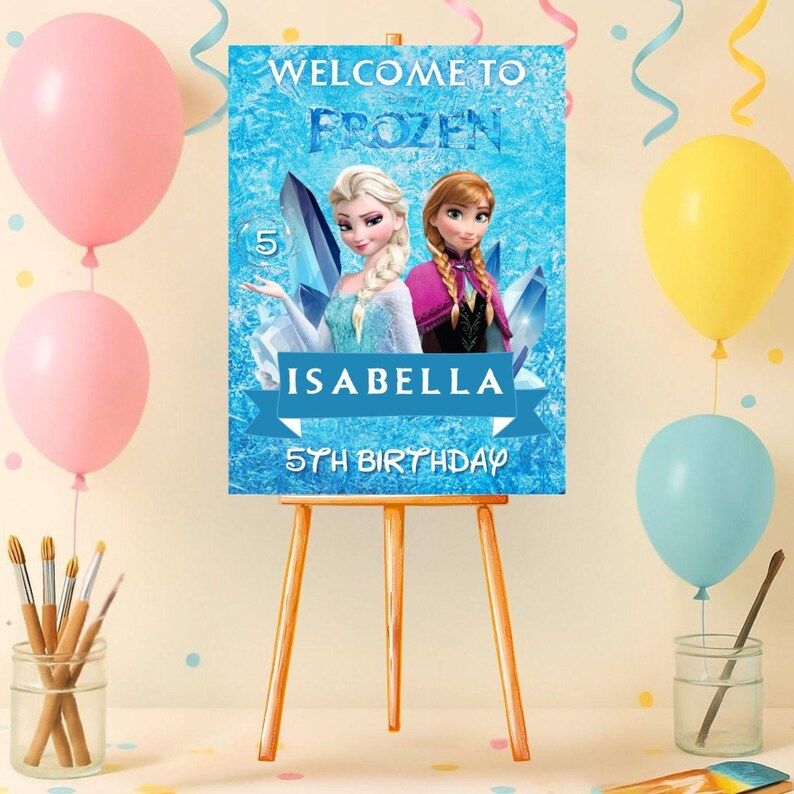 May include: A wooden easel holds a blue sign featuring Elsa and Anna from Frozen, with the text "Welcome to Frozen." The sign is for "Isabella's 5th Birthday." Pink, yellow, and blue balloons and paintbrushes decorate the scene.