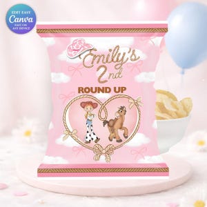 May include: Pink party bag with a cowboy theme. The bag features the text "Emily's 2nd Round Up" and illustrations of a cowgirl and a horse inside a heart-shaped rope design. A cowboy hat and clouds are also featured.