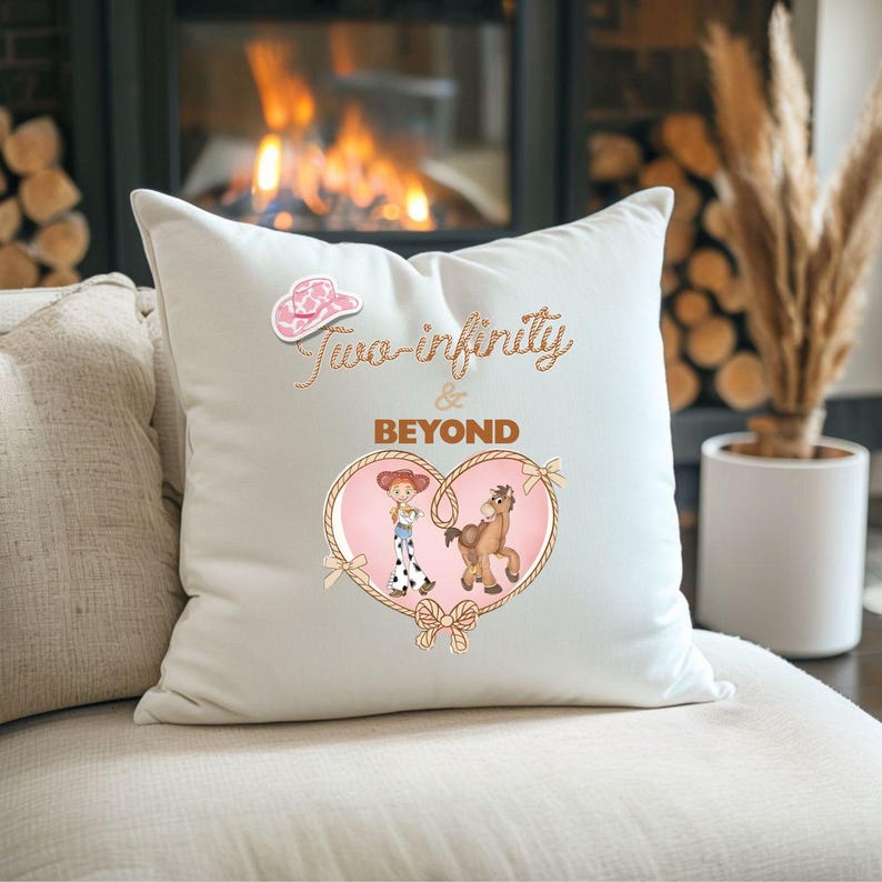 Peut inclure: Un coussin blanc d&eacute;coratif avec le texte "Two-infinity & BEYOND" en &eacute;criture cursive. Le coussin pr&eacute;sente un chapeau de cowboy rose et un motif en forme de c&oelig;ur avec des personnages de dessins anim&eacute;s et un cheval.
